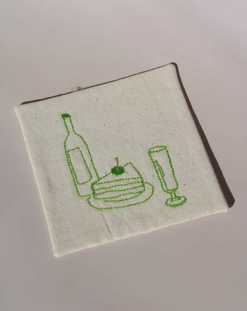 Maison Handsewn Embroidered Coaster with green stitched wine bottle, cake slice, and champagne glass motif on natural cotton fabric.