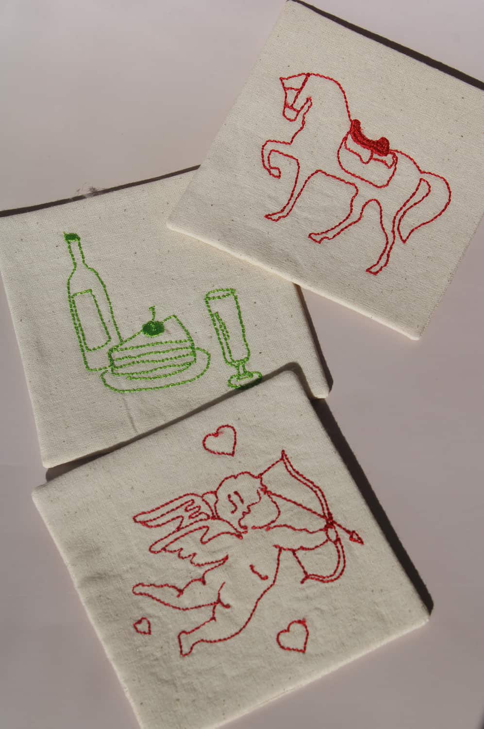 Cavalier, Maison, and Amour Handsewn Embroidered Coasters with horse, wine, and cupid motifs stitched on natural cotton handmade drink coasters.