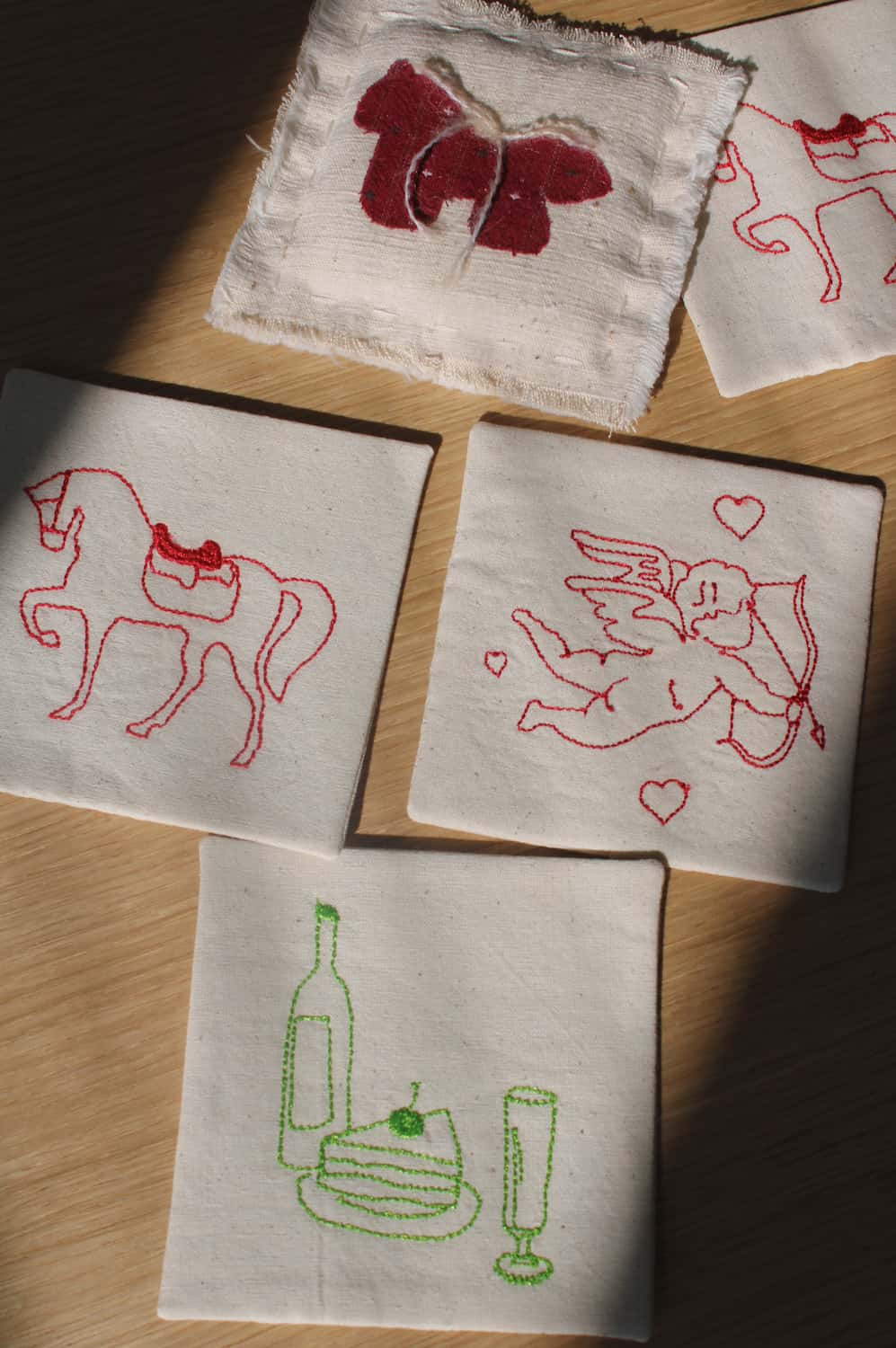 Cavalier, Maison, and Amour Handsewn Embroidered Coasters with horse, wine, and cupid motifs stitched on natural cotton handmade drink coasters.