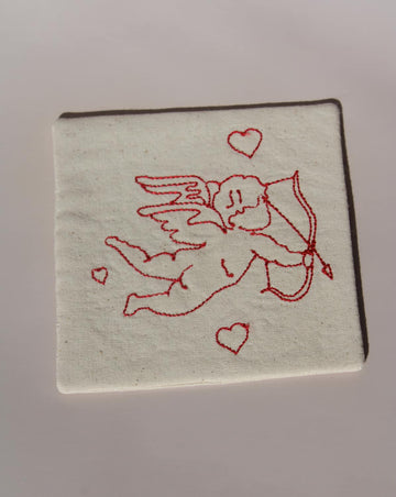 Amour Handsewn Embroidered Coaster with cupid and heart motif stitched in red on natural cotton handmade drink coaster.