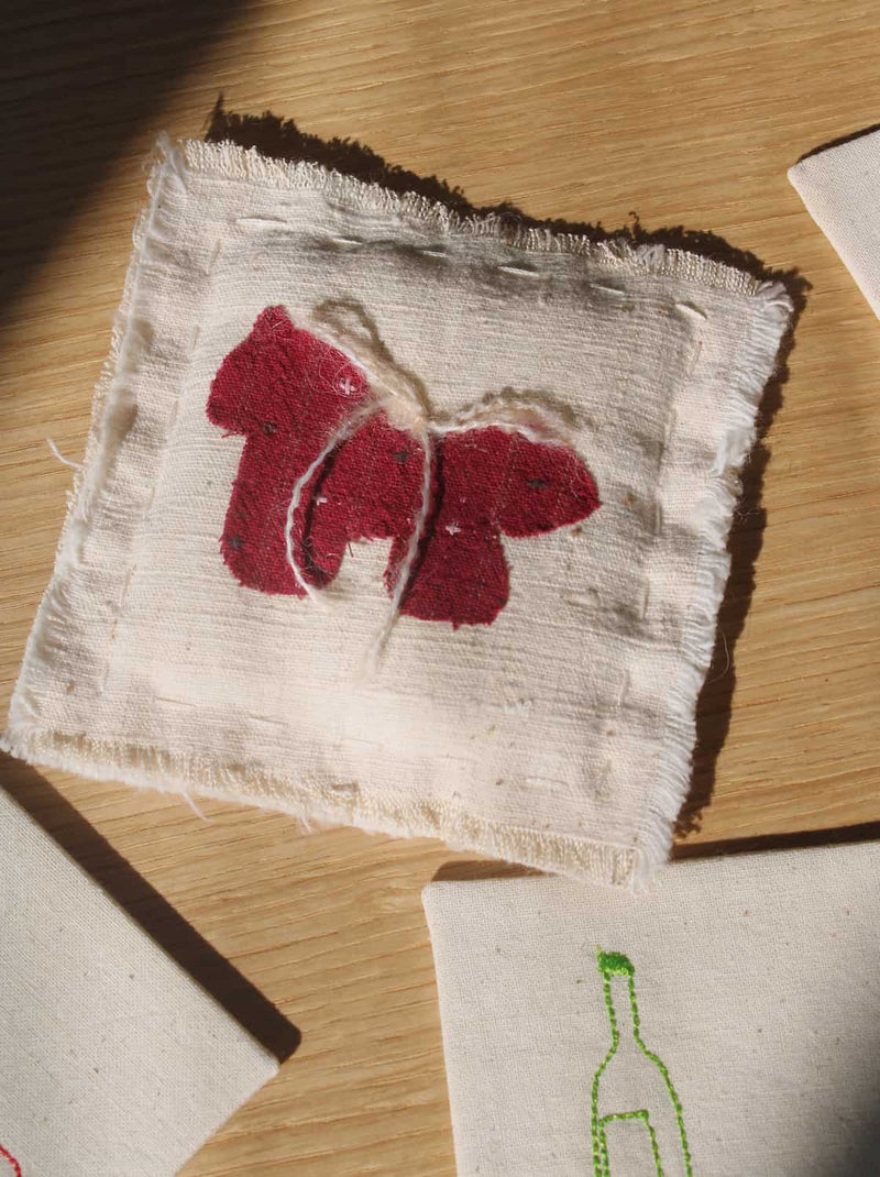 Écurie handmade horse coaster with red embroidered horse design on natural cotton fabric, hand-sewn textile coaster.