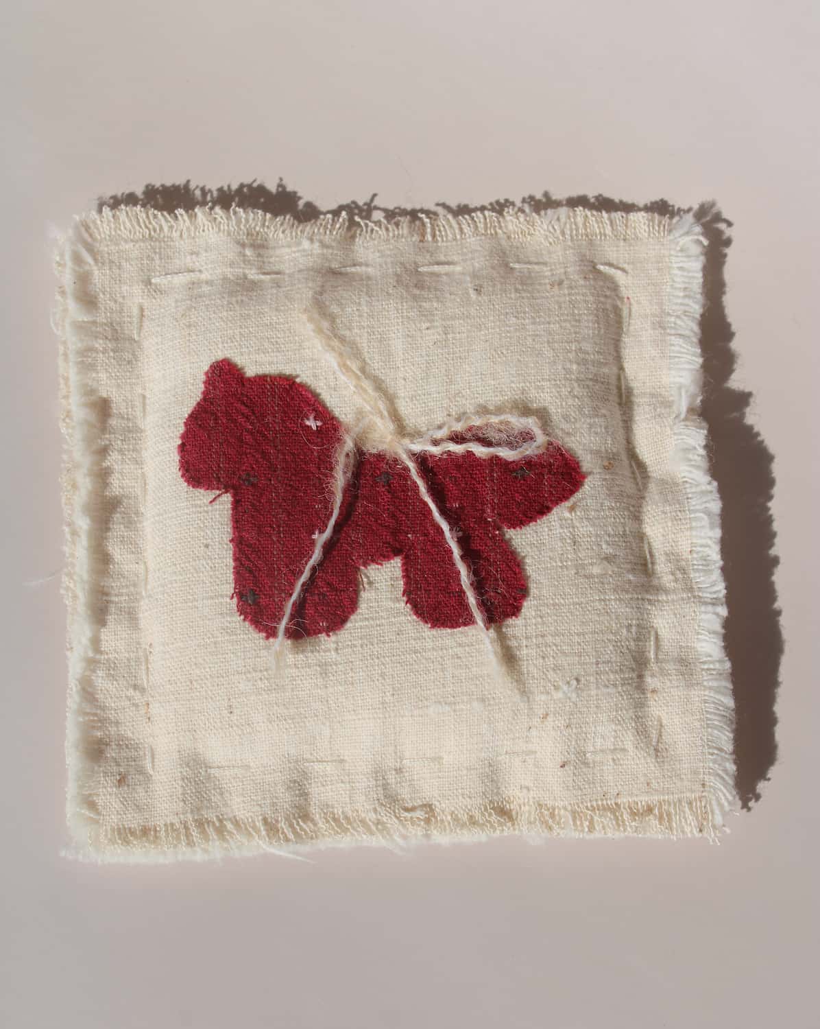 Écurie handmade horse coaster with red embroidered horse design on natural cotton fabric, hand-sewn textile coaster.