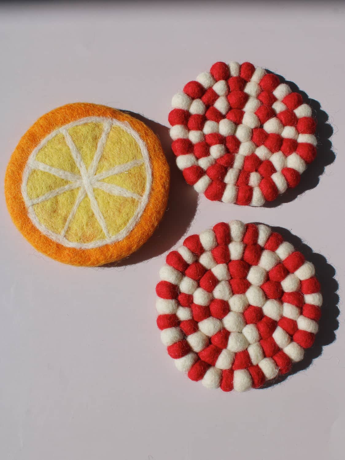 Clementine and Bonbon Handmade Coasters together, felted wool citrus-slice and candy-stripe coaster set