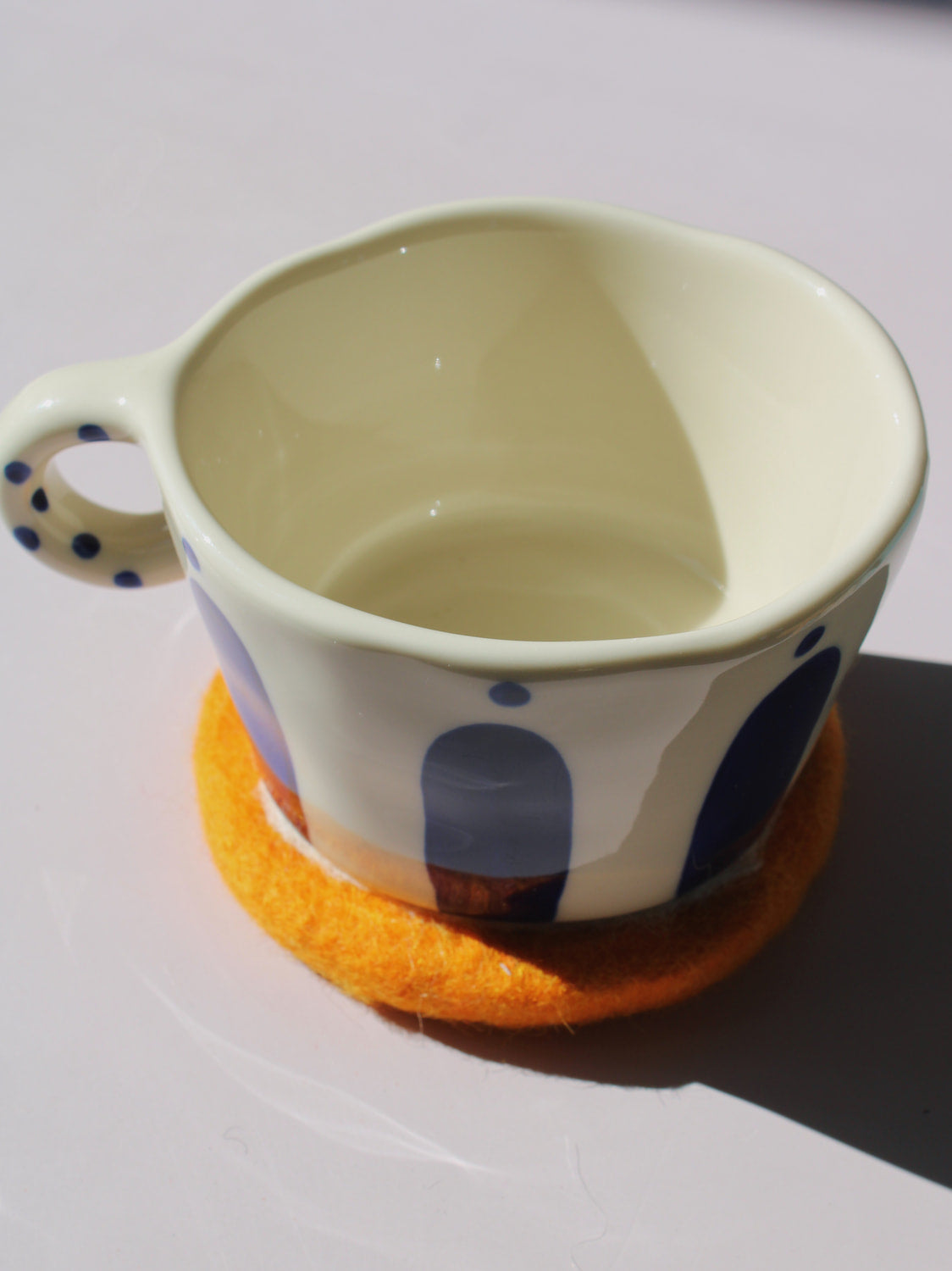 Ceramic mug with blue polka dot design on an orange coaster