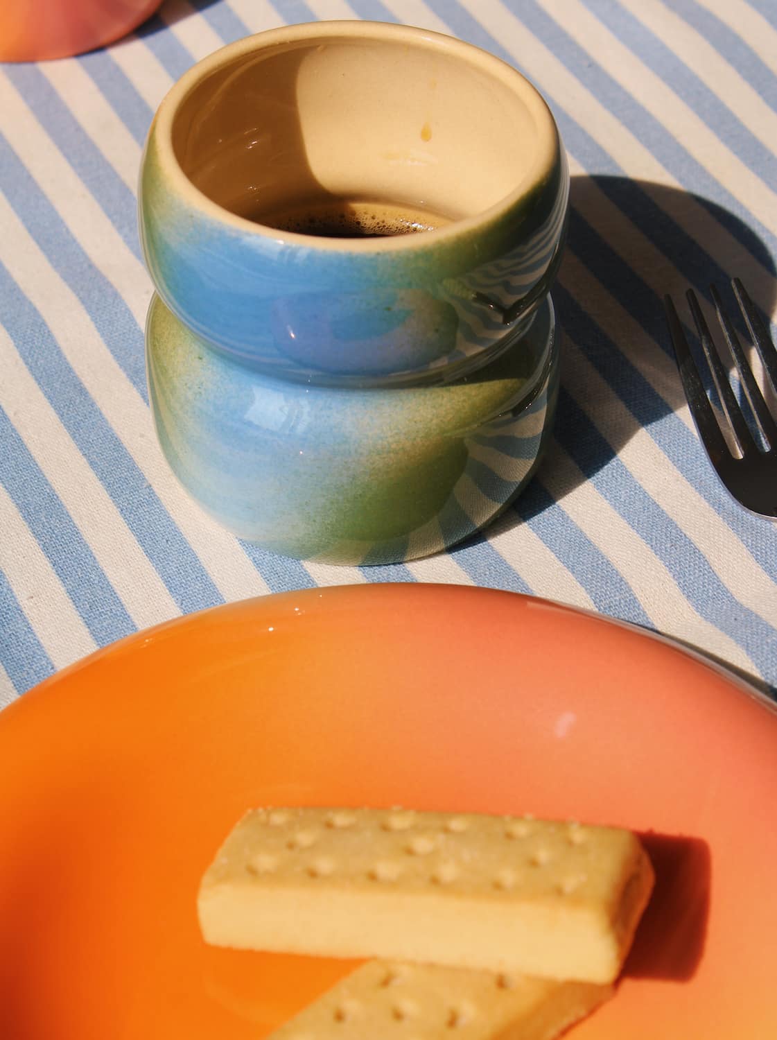 Handmade Belly Dew cup paired with dessert plate in warm morning light setting.