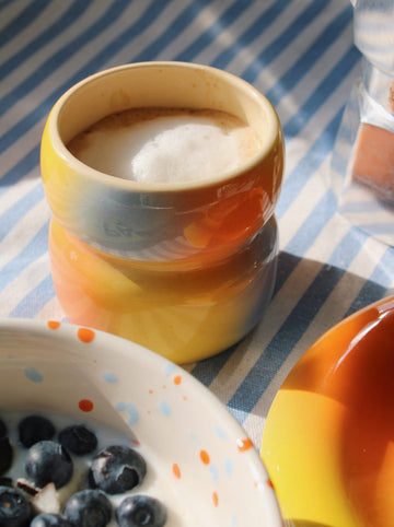 Belly summertime ceramic mug with warm gradient glaze and coffee, close-up of handcrafted cup in soft light