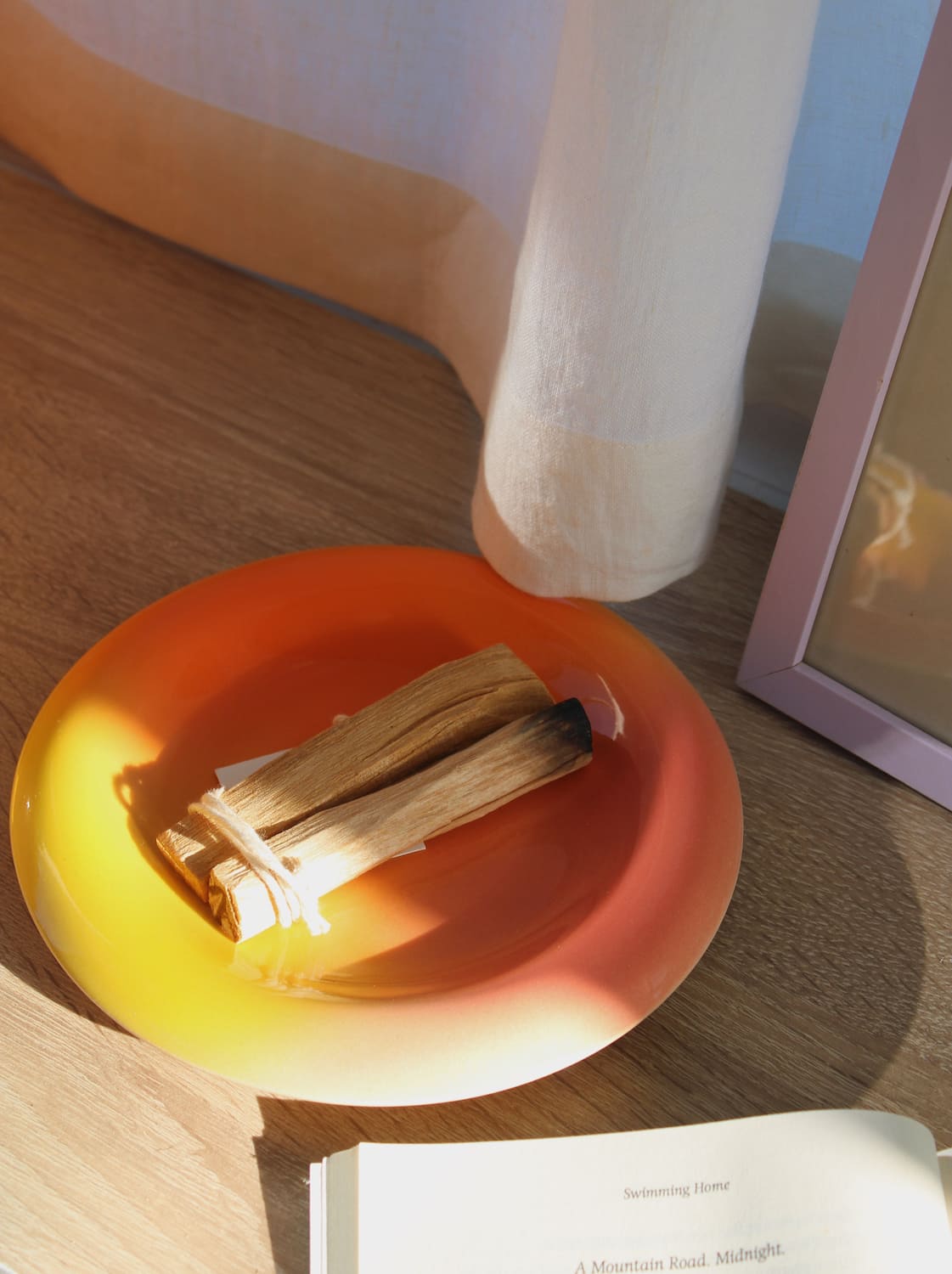 Belly Sunset plate in gradient yellow to red-orange glaze, styled with palo santo sticks on an oak surface