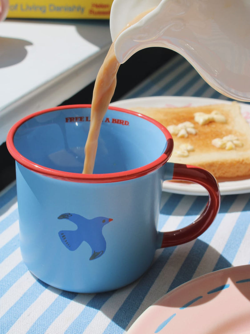 Birdie ceramic mug in warm sunlight, blue and red handmade mug for relaxed morning coffee
