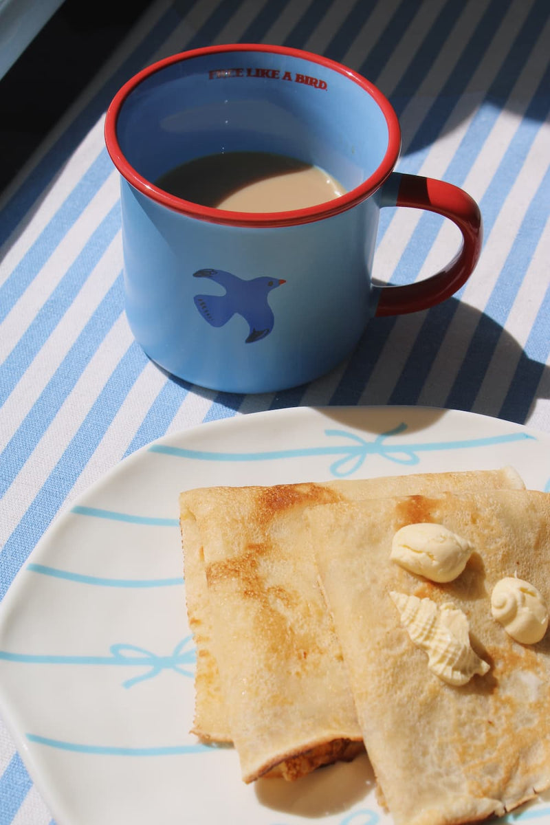 Birdie ceramic mug in warm sunlight, blue and red handmade mug for relaxed morning coffee