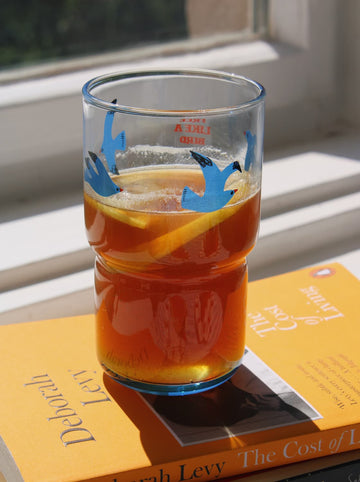 Glass of iced tea with lemon slices on a book, sunlight streaming through a window.