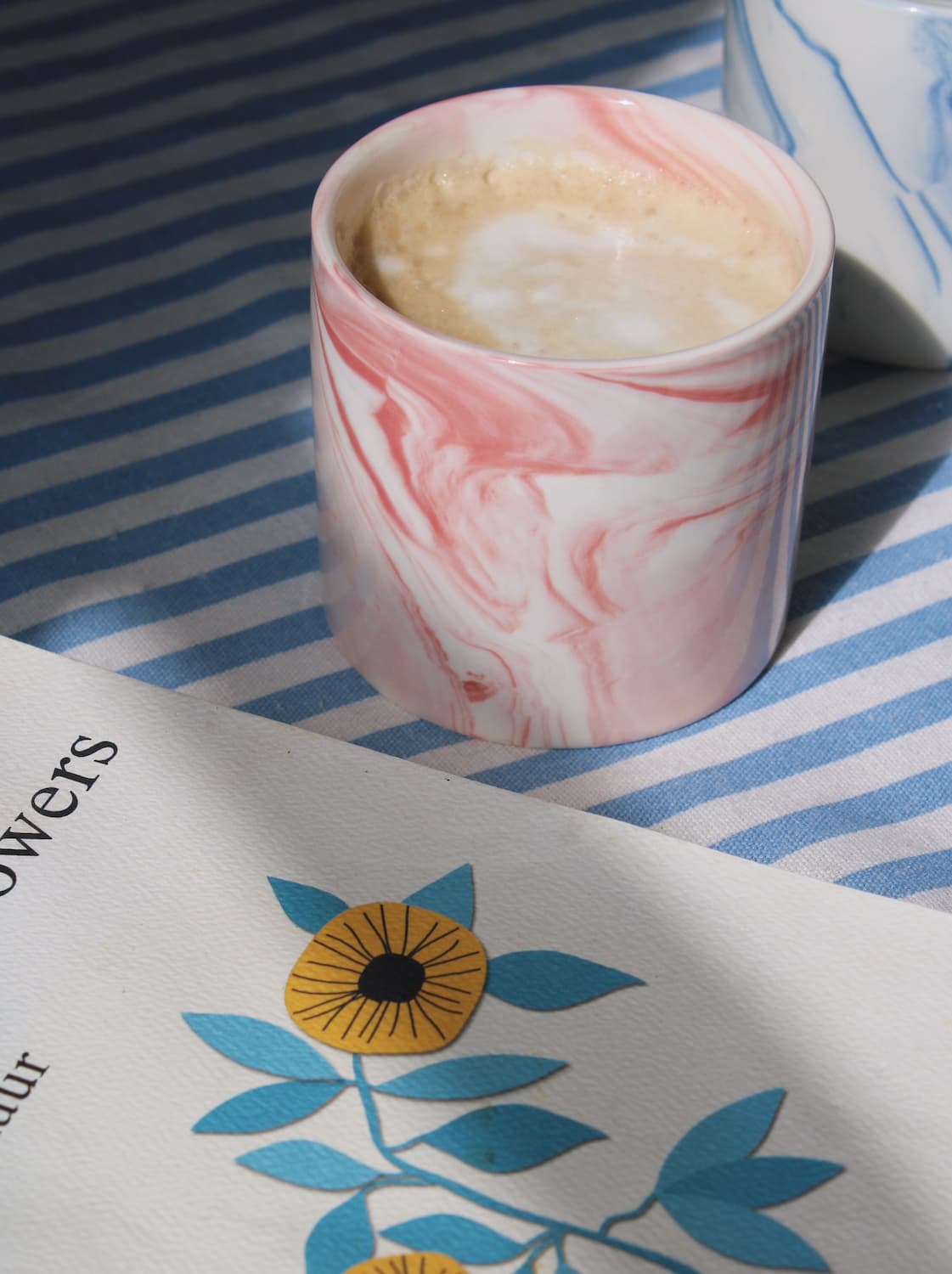 Blush ceramic cup with soft pink glaze styled on striped tablecloth in natural light