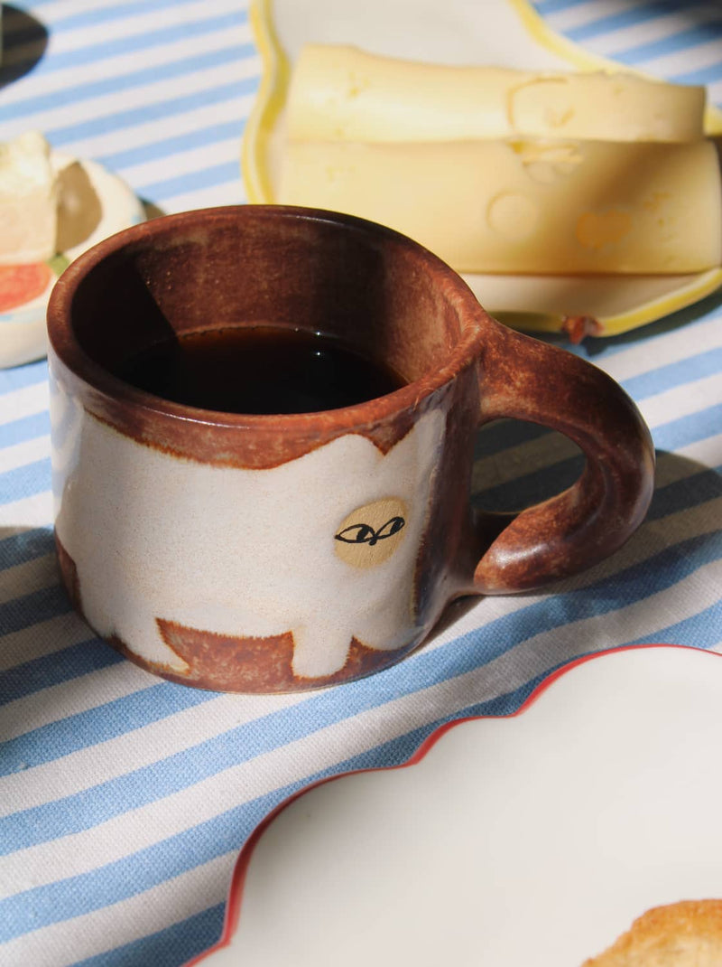 Chestnut ceramic mug with warm brown glaze and coffee on striped tablecloth