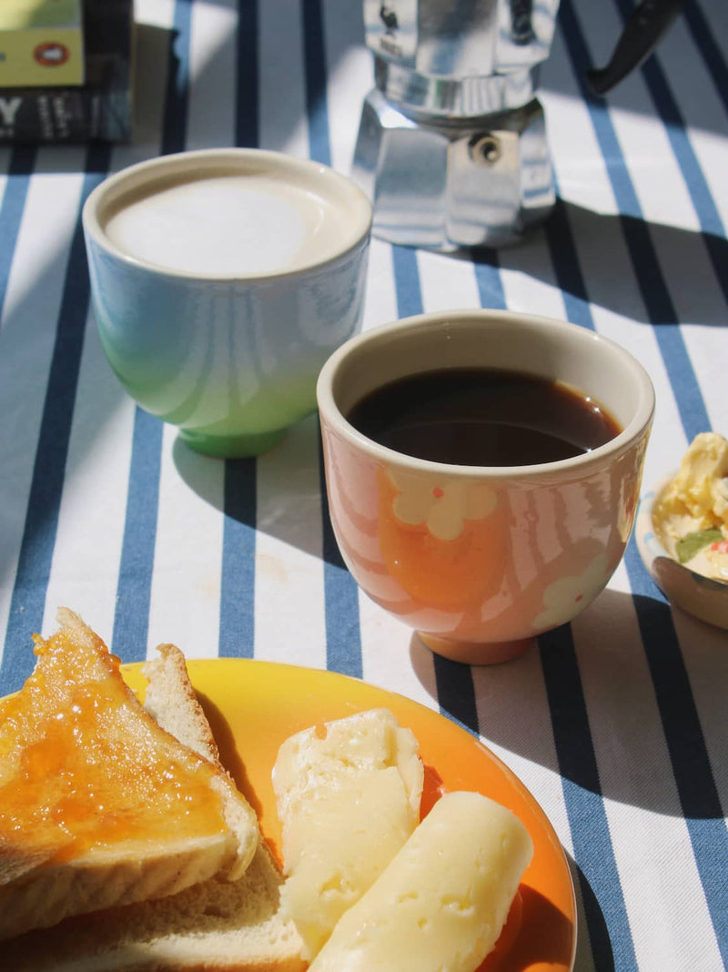 garden yunomi cup and sky yunomi cup on a striped table cloth with breakfast