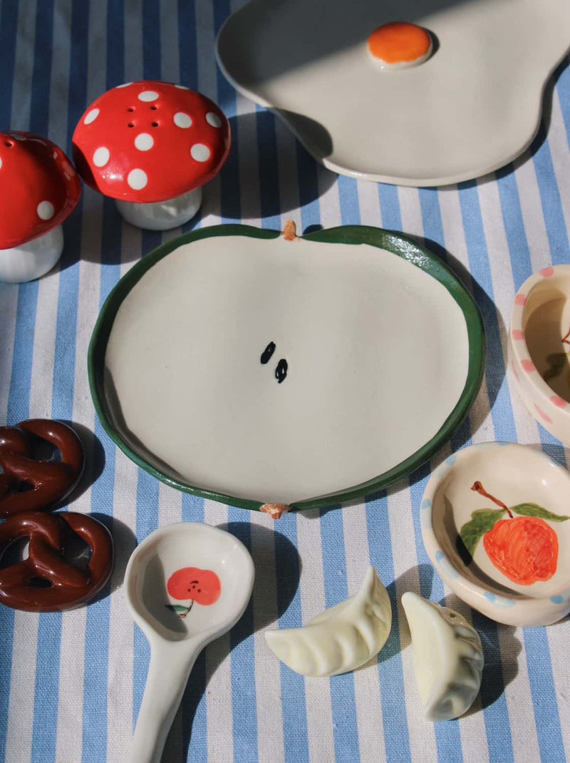 Ceramic spoon rest and chopstick rests with fruit motifs and dumpling shapes, styled with playful handmade tableware