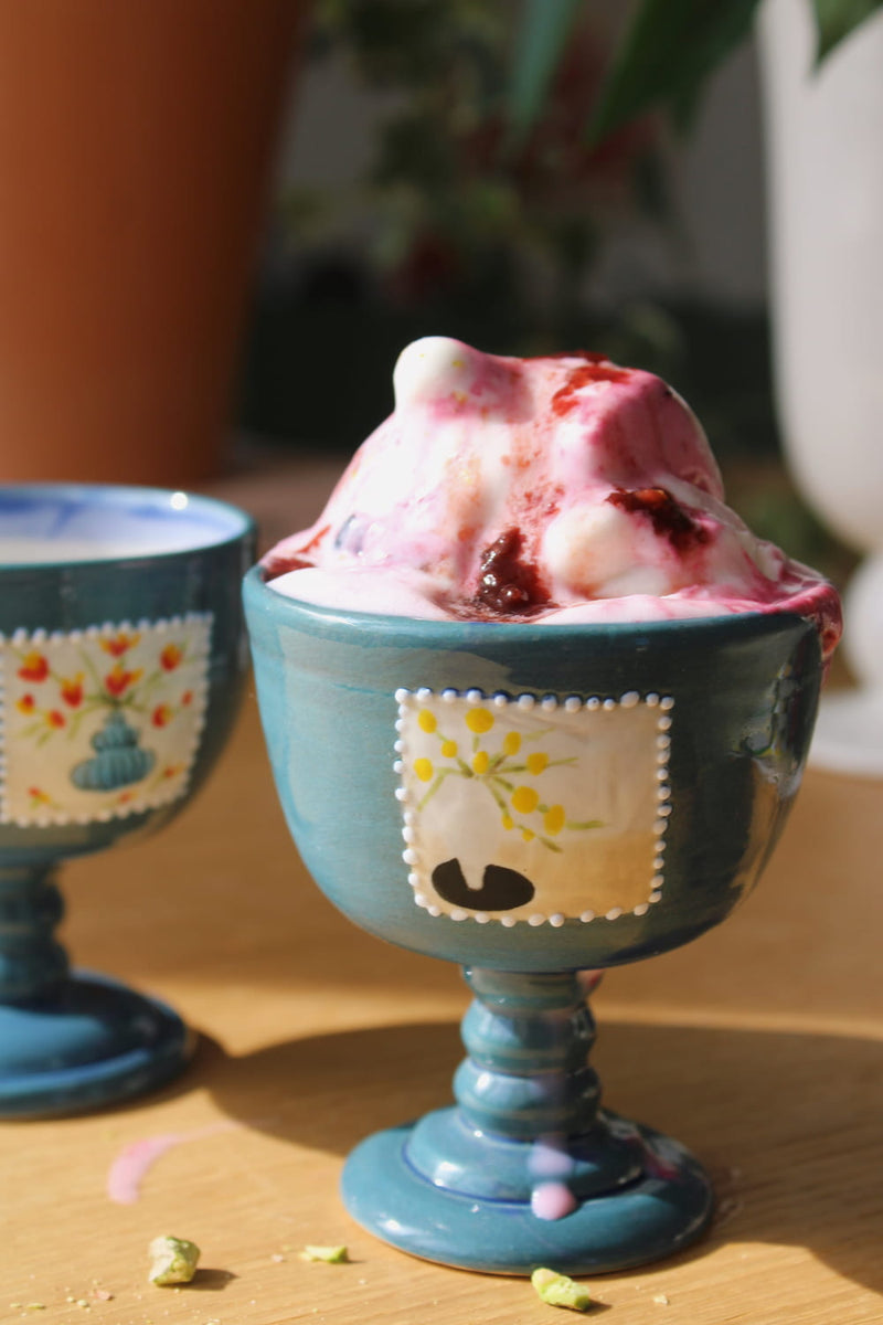 Blue ceramic ice cream goblet with strawberry ice cream on a wooden surface