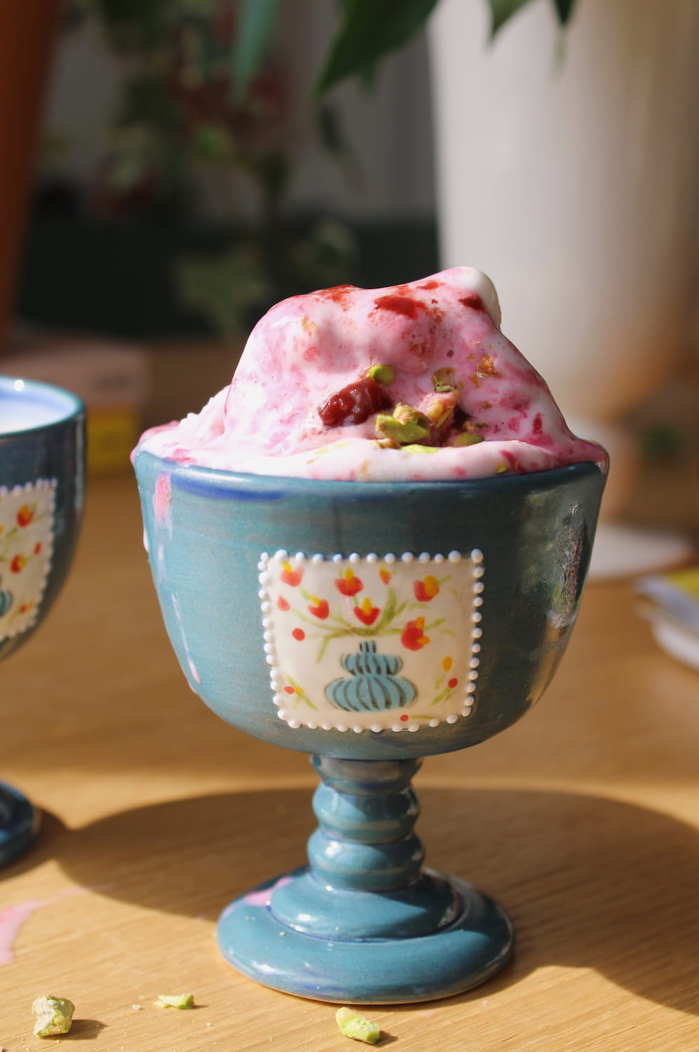Pink ice cream in a decorative blue ceramic goblet on a wooden surface