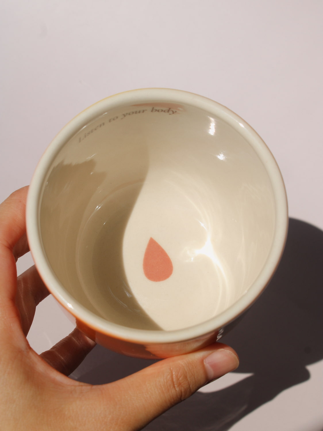Gradient ceramic mugs in warm orange yellow and pink tones with "Listen to your body" printed inside the rim, handmade in small batches — Listen to Your Body limited edition ceramic mug bladder cancer awareness collection