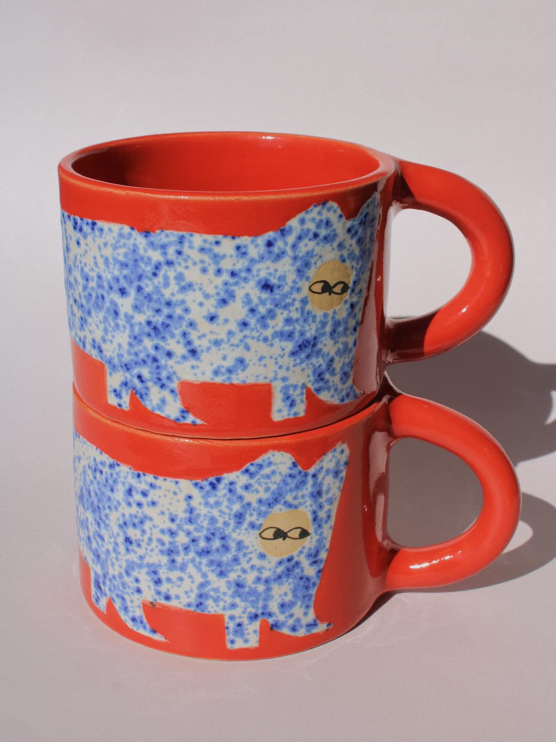 Scarlet Ceramic Cat Mugs by Marta Shurpakova – two stacked handmade ceramic mugs with hand-painted cat designs 
