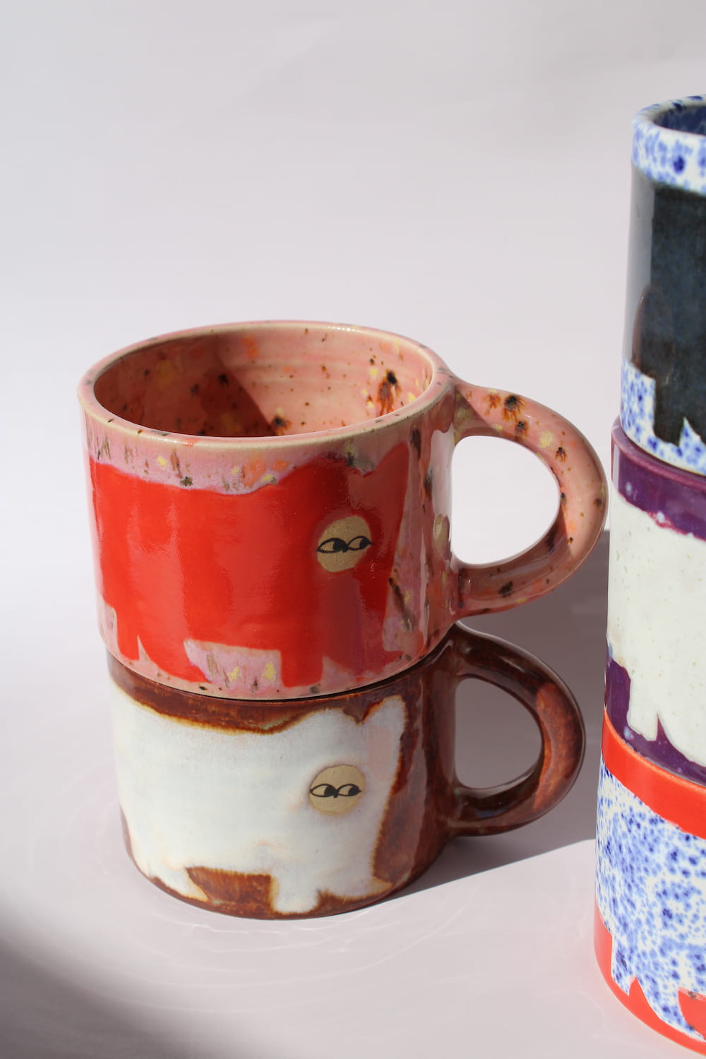 Handmade ceramic cat mugs by Marta Shurpakova – two colourful illustrated mugs in different designs and glazes