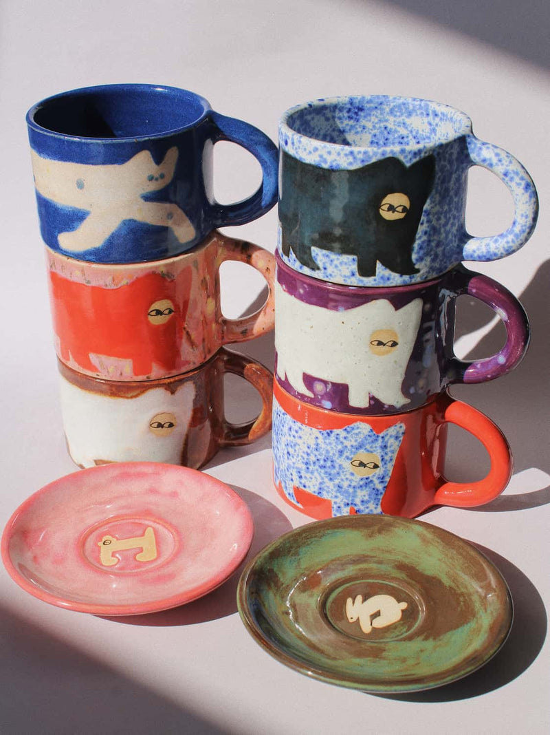 Ceramic Cat Mugs by Marta Shurpakova – six stacked handmade ceramic mugs with hand-painted cat designs 