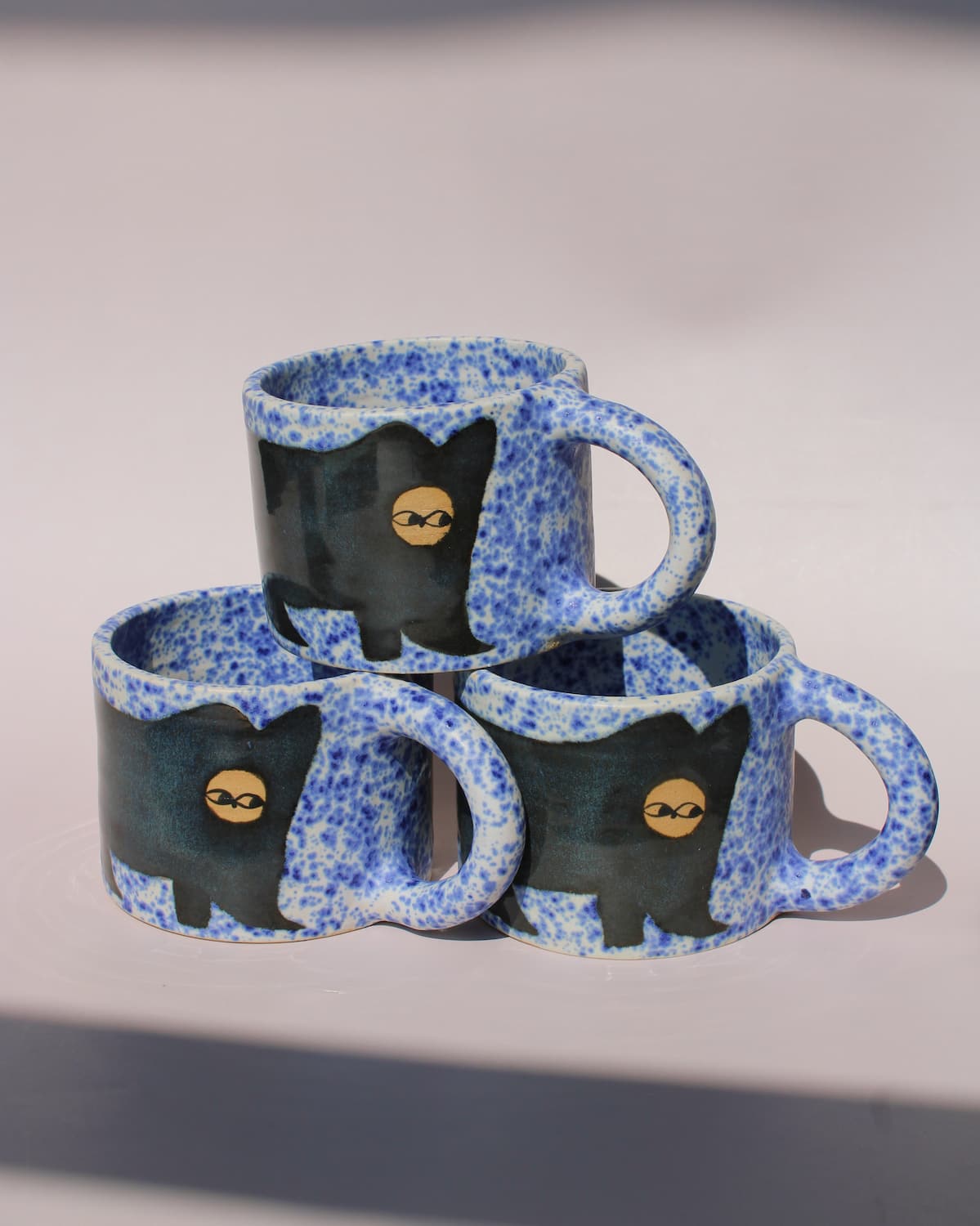 Midnight Cat Ceramic Mug by Marta Shurpakova – three handmade blue ceramic mugs with playful black cat designs