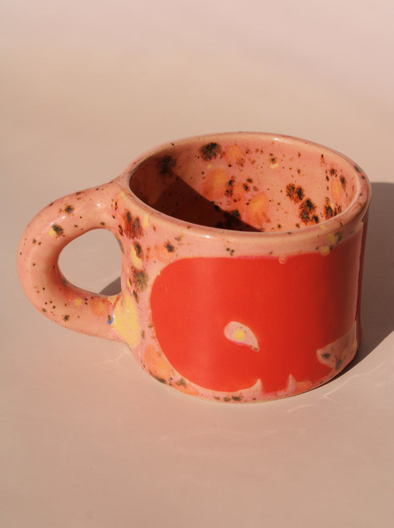 Pink ceramic mug with speckled pattern on a beige background