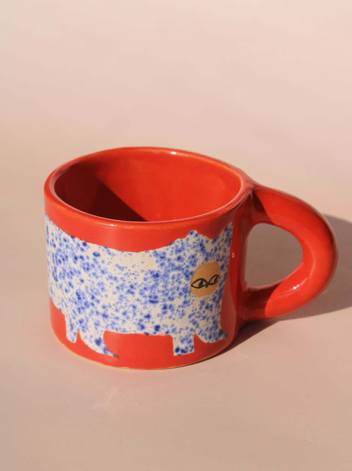 Red mug with a blue and white pattern of a bear on a beige background