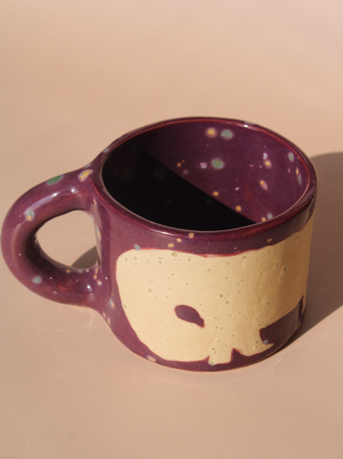 Speckled purple mug with a beige elephant design on a beige background