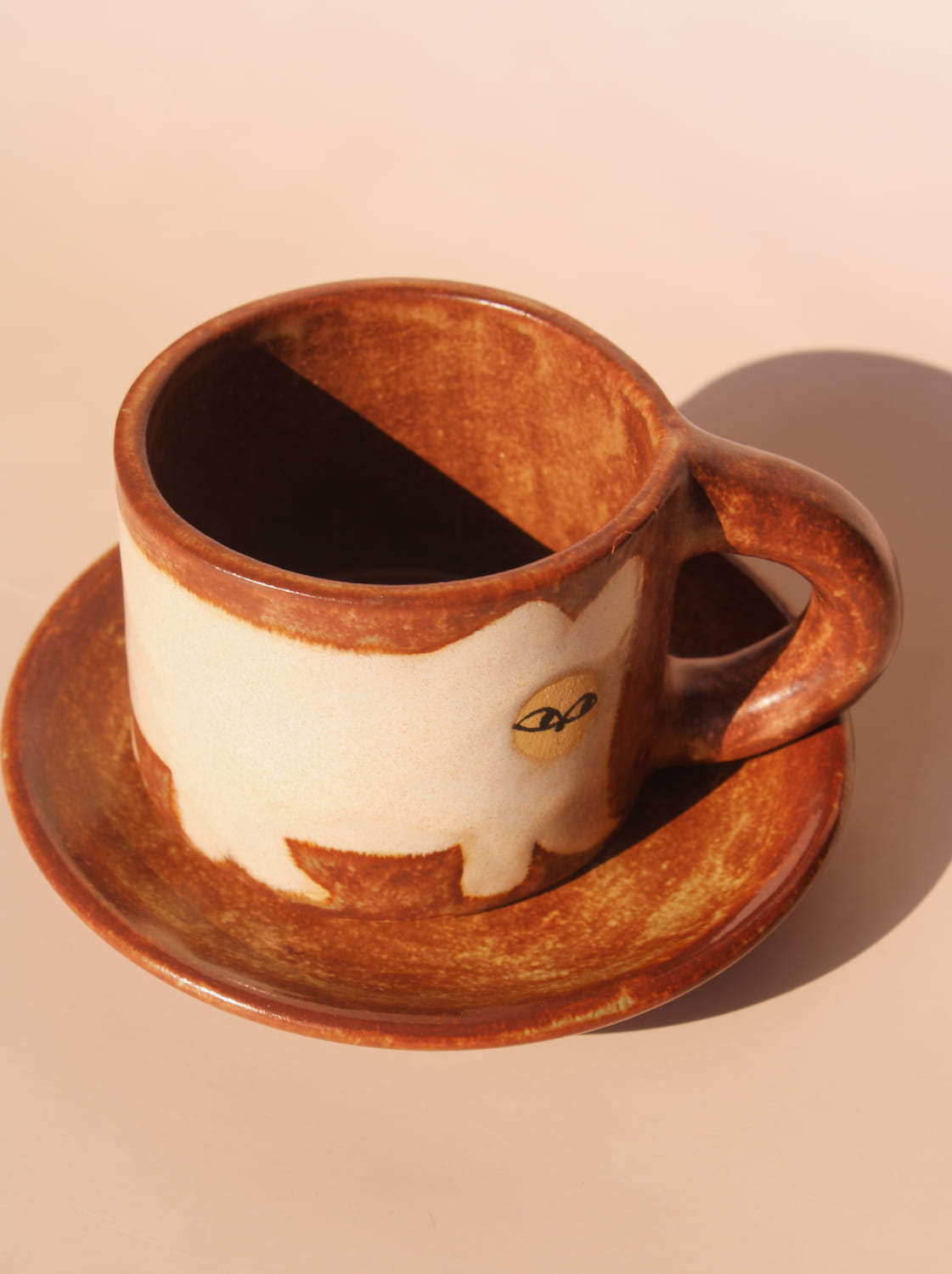 Ceramic cup and saucer with a cat design on a beige background