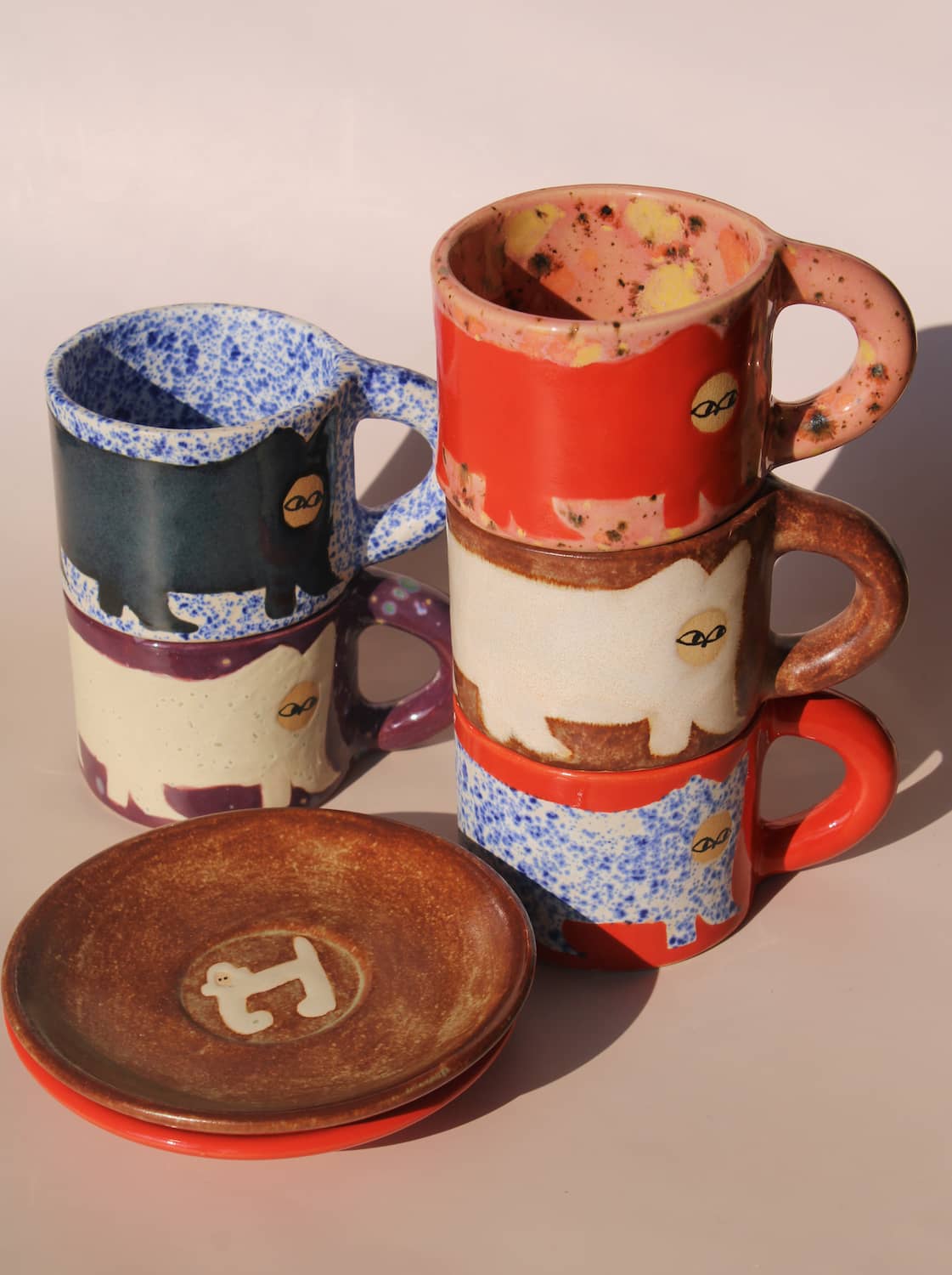 Set of ceramic mugs and a plate with animal designs on a beige background