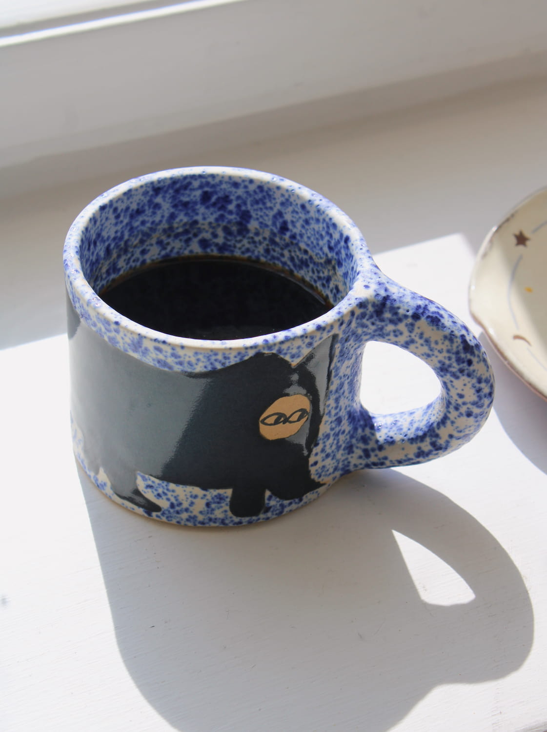 Blue speckled mug with a bear design on a white surface
