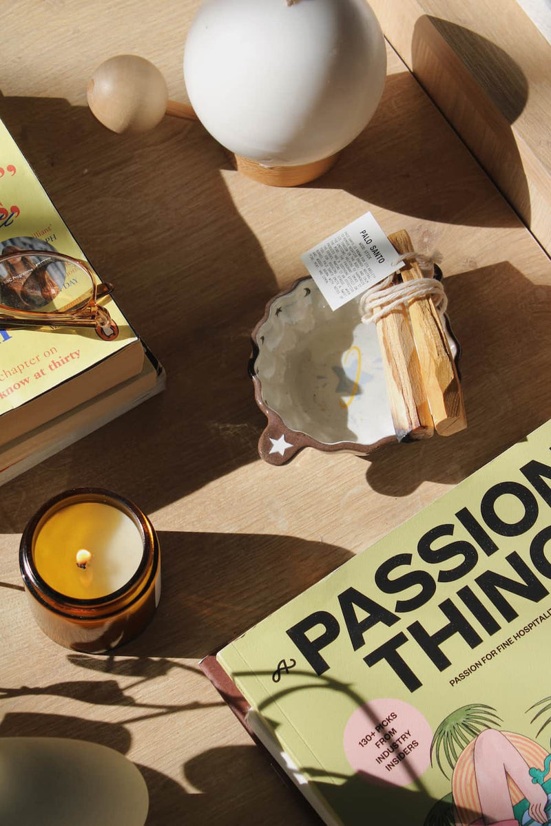 Candle, books, and decorative items on a wooden surface with soft lighting.