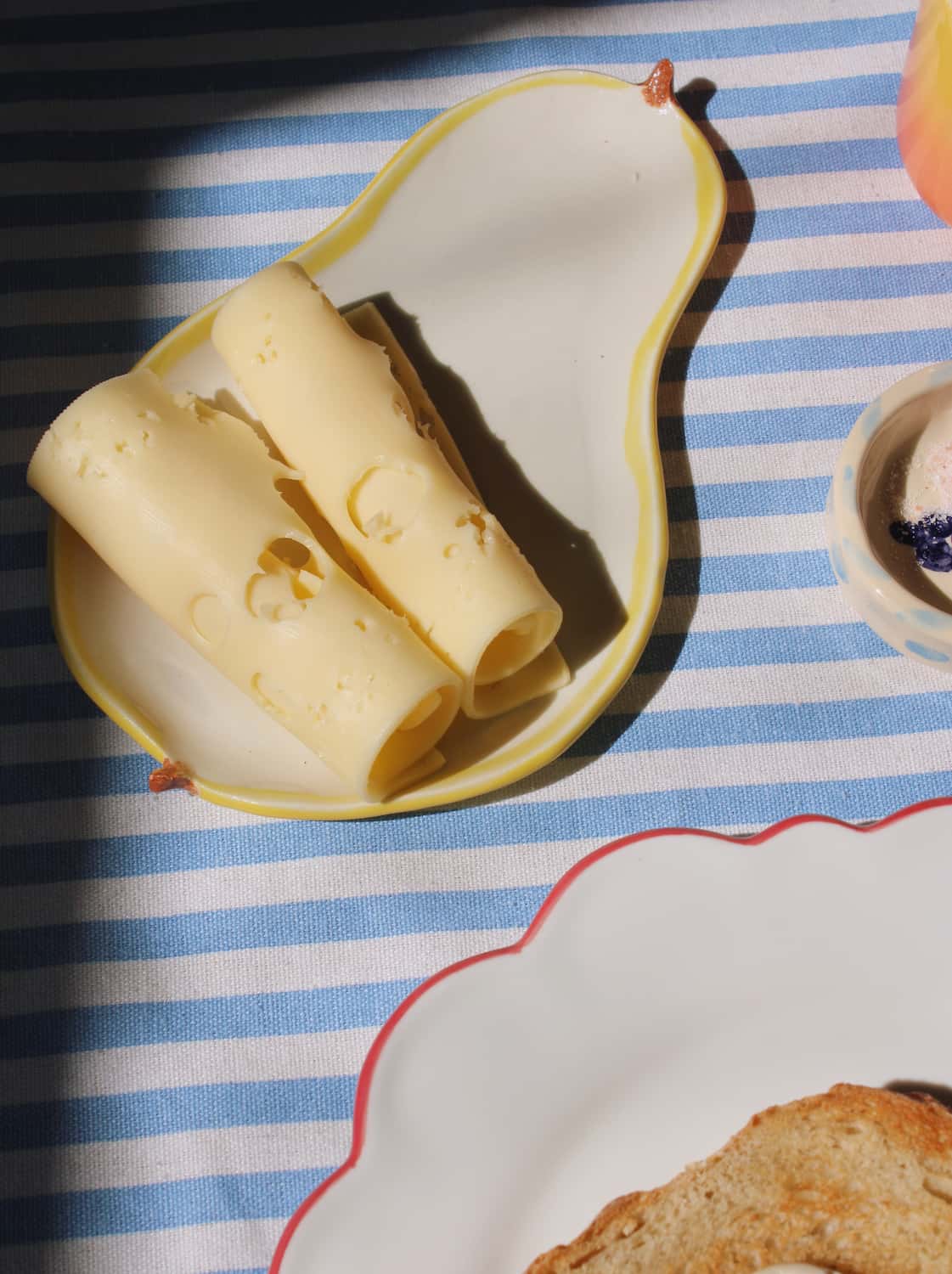 Pear ceramic spoon rest with cheese curls and tableware in warm sunlight