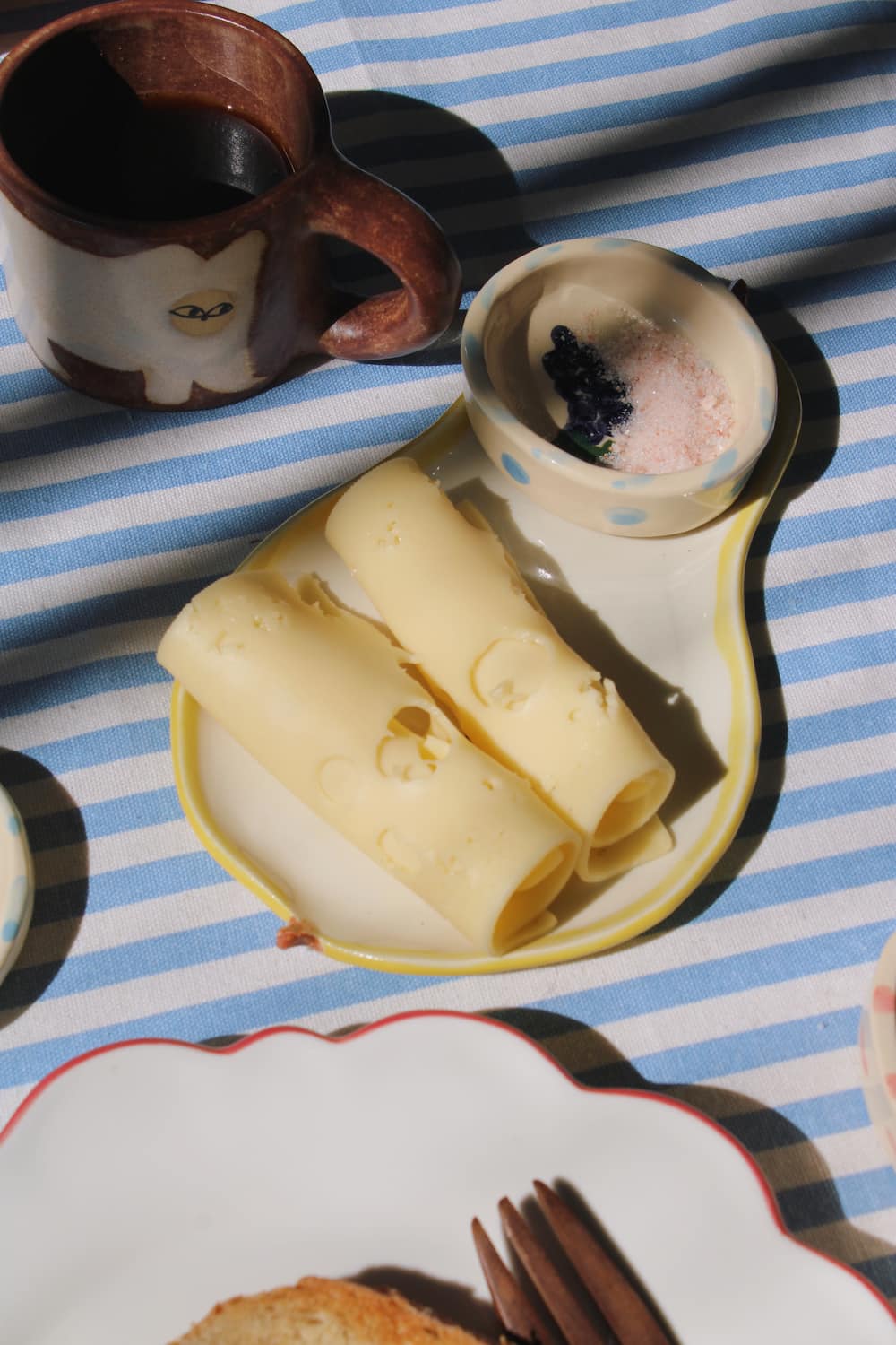 Pear ceramic spoon rest with butter curls and tableware in warm sunlight