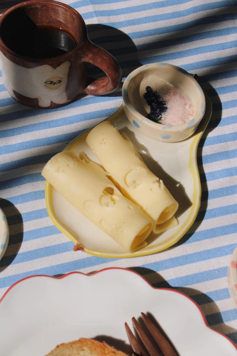 Pear ceramic spoon rest with butter curls and tableware in warm sunlight