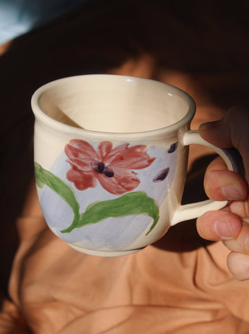 Handmade Petalia mug with bold flower motif held in hand in soft natural light