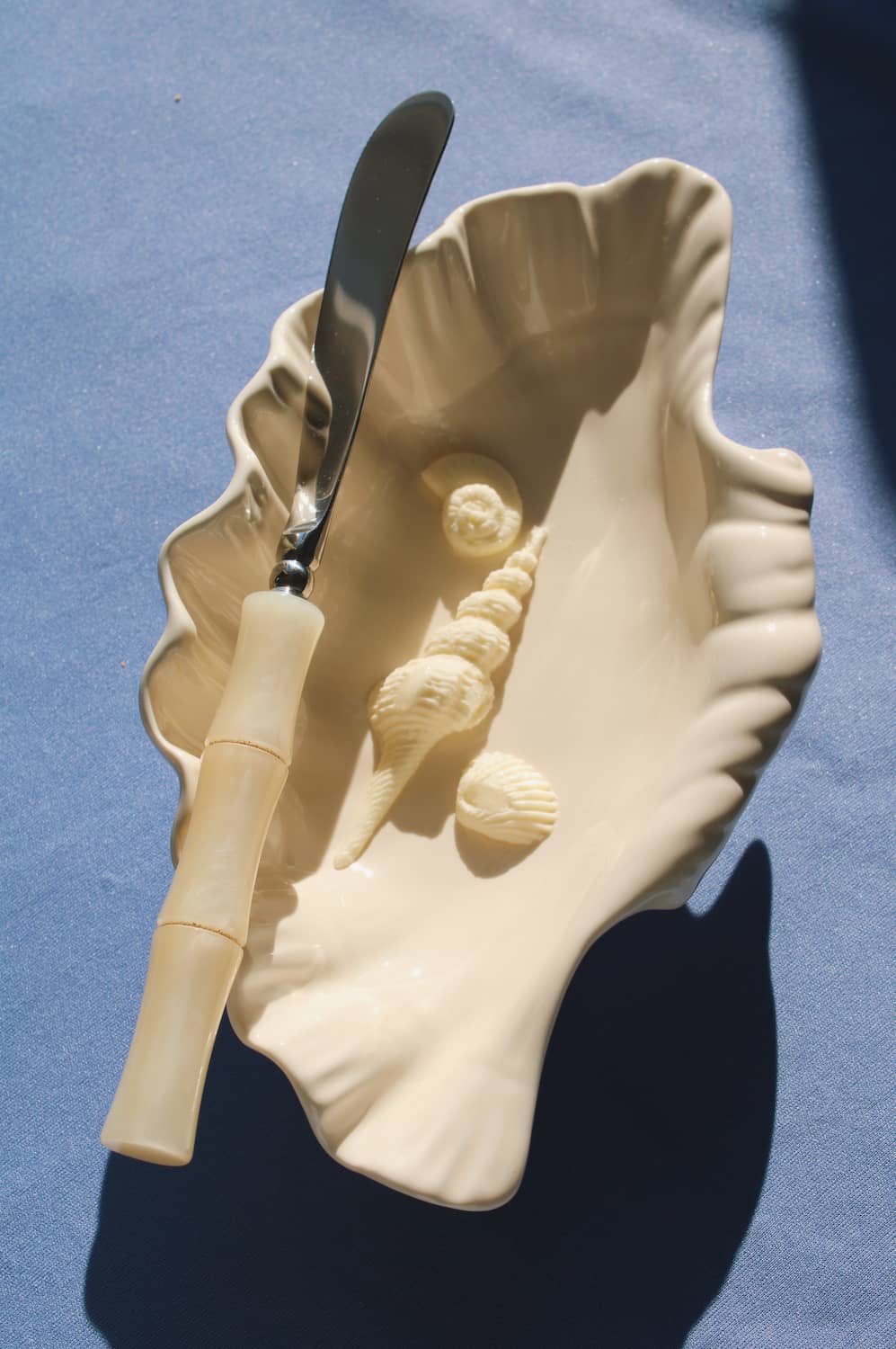 Shell-shaped dish with a knife and decorative elements on a blue background
