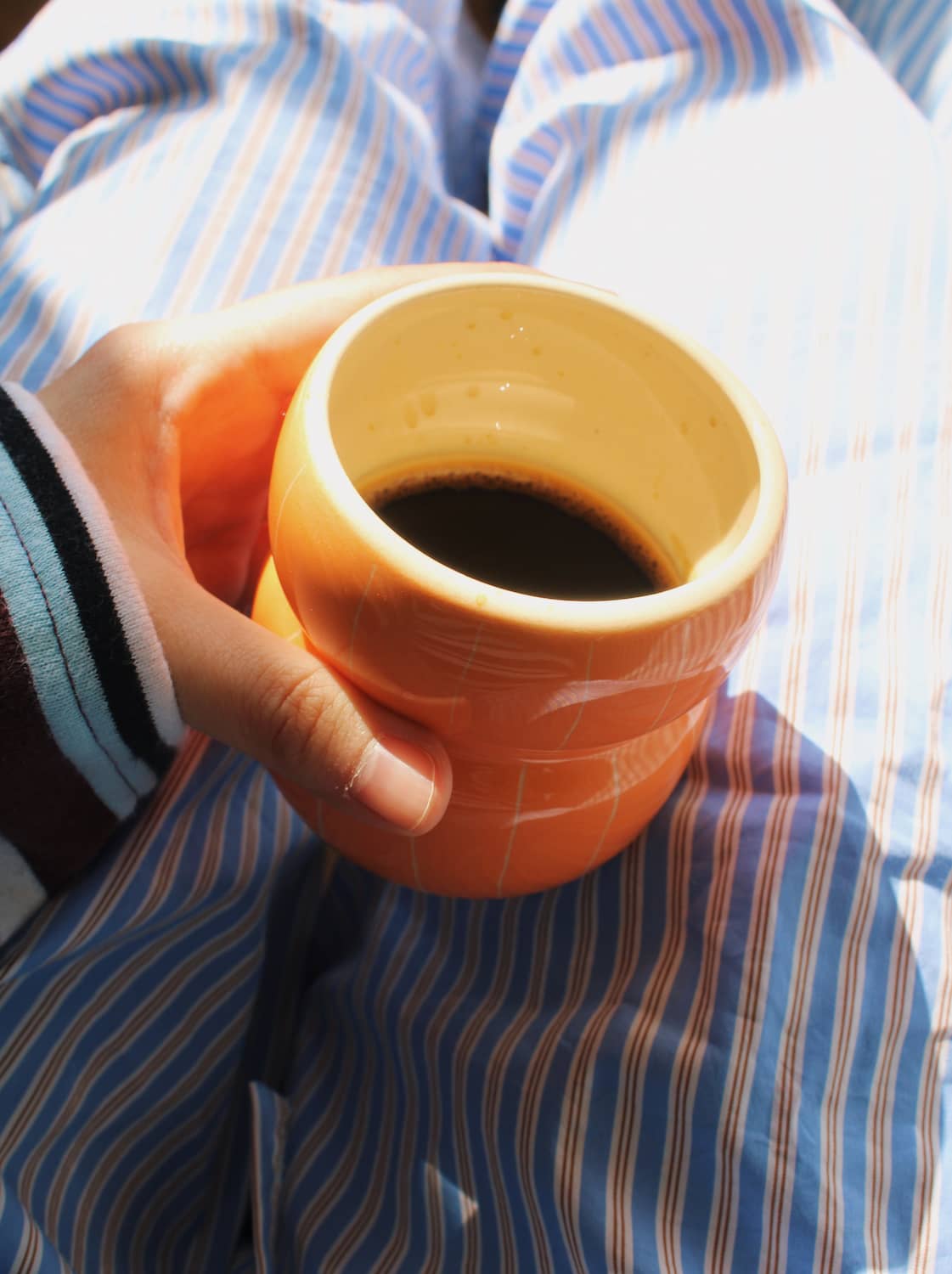 Tangerine ceramic coffee cup in hand, handmade mug with soft orange glaze for everyday use